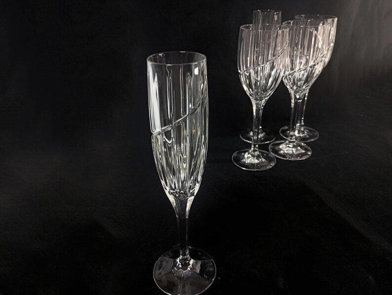Vintage Mikasa Uptown clear heavy cut crytal stemware. This 5 piece set consists of three 9 inch water goblets and two 9 1/2 inch fluted champagne glasses. The bowls are vertically cut and polished from the rim to the stem and one horizontal spiral around the bowl. The tall slender stems are six-sided and curver gracerully into thesix-segmented foot.