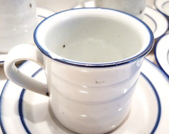 May include: A set of white ceramic coffee mugs with blue trim. The mugs have a simple, elegant design and are perfect for everyday use.