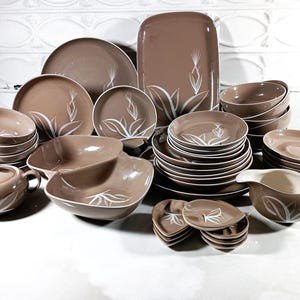 May include: A set of brown and white patterned ceramic dinnerware. The set includes plates, bowls, a serving dish, a creamer, and a sugar bowl.