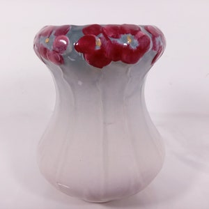 May include: White ceramic vase with a scalloped rim and red floral design.