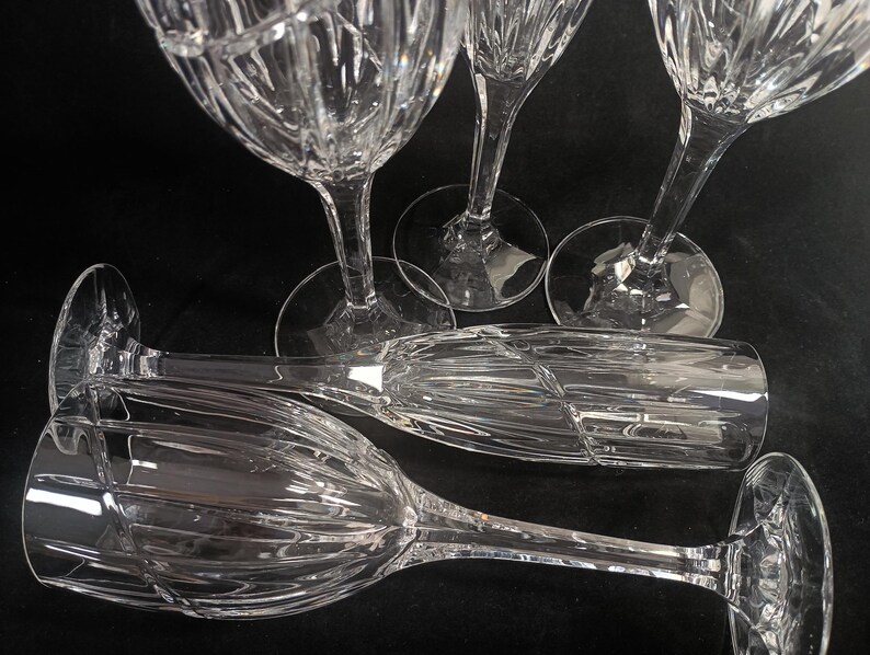 Vintage Mikasa Uptown clear heavy cut crytal stemware. This 5 piece set consists of three 9 inch water goblets and two 9 1/2 inch fluted champagne glasses. The bowls are vertically cut and polished from the rim to the stem and one horizontal spiral around the bowl. The tall slender stems are six-sided and curver gracerully into thesix-segmented foot.