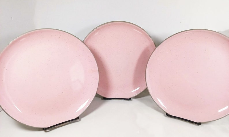 Three shell pink Harker Ware dinner plates with a gray underside.