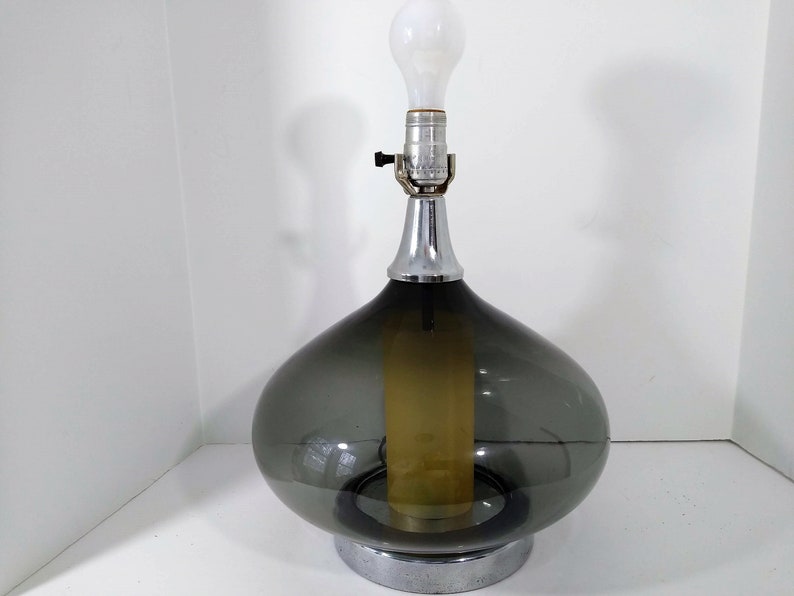 Mid Century Modern Minimalist Blenko Art Glass Table Lamp. Hand blown smoke glass garlic shape body, chrome finish neck and base. Fiberglass light diffuser inside glass body for mood light.