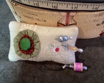 Upcycled quilt pin cushion with decorative pins and scissors charm