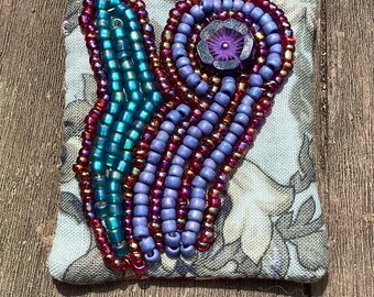 Small beaded abstract flower on blue pin brooch