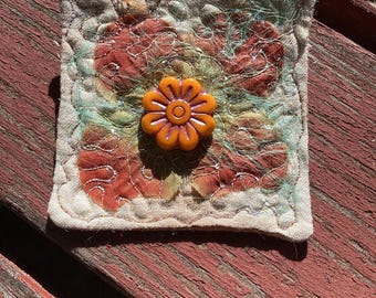Heavily quilted flower brooch with Angelina fibers