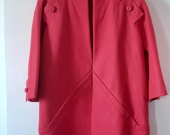 May include: A red wool coat with a mandarin collar and a V-neckline. The coat has a unique design with angled seams and decorative buttons on the shoulders.