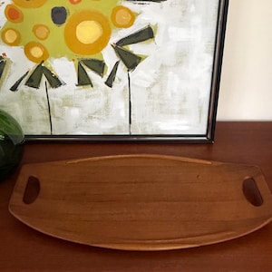 Puede incluir: Una bandeja de servir de madera con dos asas. La bandeja es de forma ovalada y tiene un acabado de madera natural.