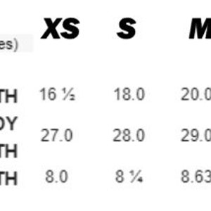 May include: A size chart in inches for apparel, featuring columns for XS, S, M, L, and XL. Rows list Body Width, Full Body Length, and Sleeve Length with corresponding numerical values for each size, presented in black text on a white background.