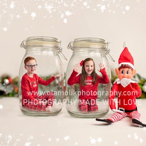 May include: Two children in red Christmas pajamas are sitting inside glass jars. A Christmas elf doll is sitting in front of the jars. The background is a light beige with white snowflakes.