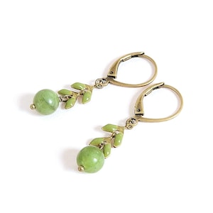 Peut inclure: Une paire de boucles d'oreilles pendantes au design inspiré de la nature. Chaque boucle d'oreille comporte une perle ronde vert clair et un groupe d'accents en forme de feuilles vert clair. Les composants métalliques ont une finition bronze.