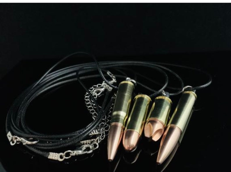 K&ouml;nnte beinhalten: Ein Satz von vier kugelf&ouml;rmigen Anh&auml;ngern an schwarzen Lederb&auml;ndern. Die Anh&auml;nger sind aus Messing und haben eine goldene Oberfl&auml;che. Die B&auml;nder sind mit einer silbernen Kette zusammengebunden.