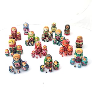 May include: A set of colorful wooden nesting dolls, also known as Russian nesting dolls or matryoshka dolls. The dolls are painted with traditional Russian folk designs and feature various female figures. The largest doll is at the top of the image, and the smallest doll is at the bottom.