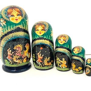 May include: A set of six Russian nesting dolls, or Matryoshka dolls, in varying sizes. Each doll features a painted face and a detailed scene on the body, with a dark blue base and a green and gold top. The dolls are arranged in a row.