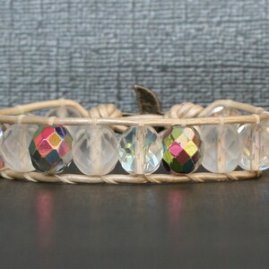 May include: A white leather wrap bracelet with iridescent crystal beads. The bracelet has a silver clasp.