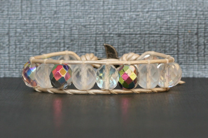May include: A white leather wrap bracelet with iridescent crystal beads. The bracelet has a silver clasp.