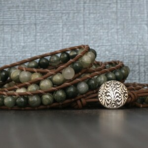 May include: A brown leather wrap bracelet with green and white gemstone beads and a silver button closure.