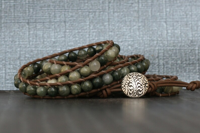 May include: A brown leather wrap bracelet with green and white gemstone beads and a silver button closure.
