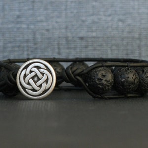 May include: Black lava rock beaded bracelet with a silver Celtic knot charm.