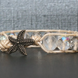 May include: A beige leather bracelet with clear glass beads and a bronze starfish charm.