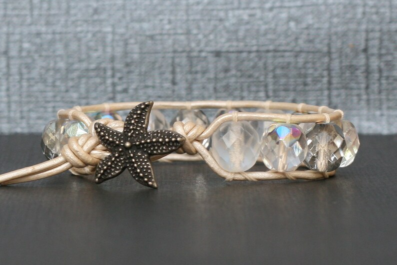 May include: A beige leather bracelet with clear glass beads and a bronze starfish charm.