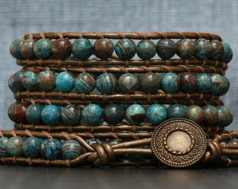May include: A multi-layered leather wrap bracelet with brown leather and blue and brown patterned beads. The bracelet has a brass clasp with a decorative design.
