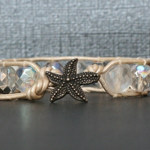 May include: A beige leather bracelet with clear iridescent glass beads and a black metal starfish charm.