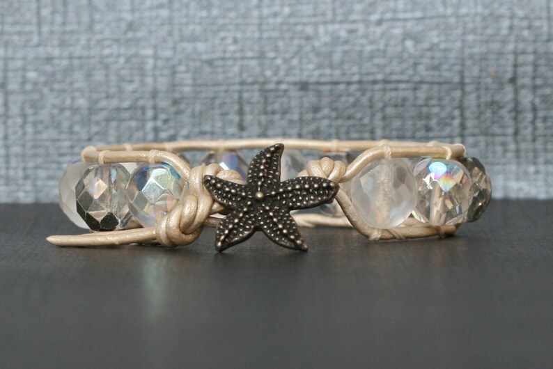 May include: A beige leather bracelet with clear iridescent glass beads and a black metal starfish charm.
