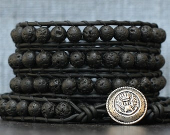 May include: A black leather wrap bracelet with multiple strands of black lava rock beads and a silver charm featuring a crown and wings.