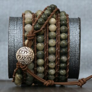 May include: A multi-strand leather wrap bracelet with green and brown gemstone beads and a silver button closure.
