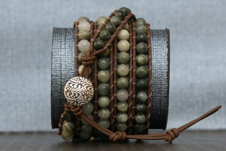 May include: A multi-strand leather wrap bracelet with green and brown gemstone beads and a silver button closure.