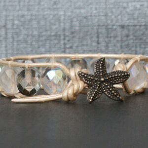 May include: A beige leather wrap bracelet with iridescent glass beads and a bronze starfish charm.