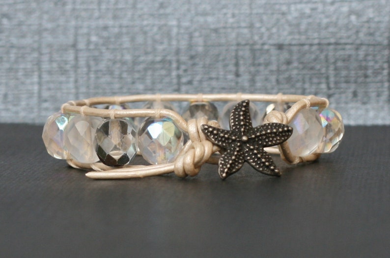 May include: A beige leather wrap bracelet with iridescent glass beads and a bronze starfish charm.