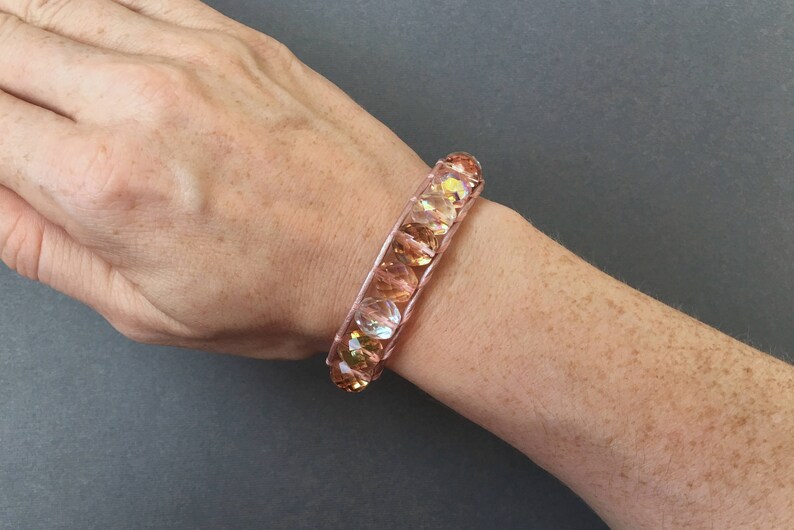 May include: A rose gold bracelet with iridescent glass beads.