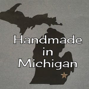 Puede incluir: Silueta del estado de Michigan con el texto "Handmade in Michigan" y una estrella dorada.