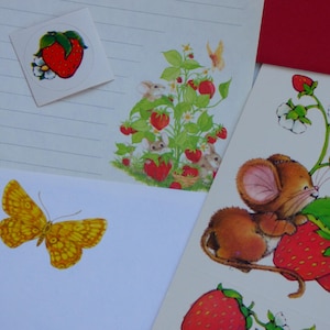 May include: Stationery set featuring white lined paper and white cardstock decorated with illustrations of red strawberries, green leaves, white flowers, small brown mice, and a yellow butterfly. The set includes a square sticker with a strawberry.