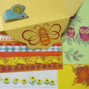 May include: A collection of stationery items featuring whimsical illustrations. Includes a yellow envelope with a blue mouse sticker, patterned paper strips with ladybugs, flowers, and mice, and cards with owls and flowers.