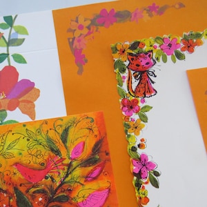 May include: A collection of vintage stationery with floral and cat illustrations. The stationery features orange, pink, and green floral designs, with a whimsical cat illustration on one piece. The overall aesthetic is retro and colorful.