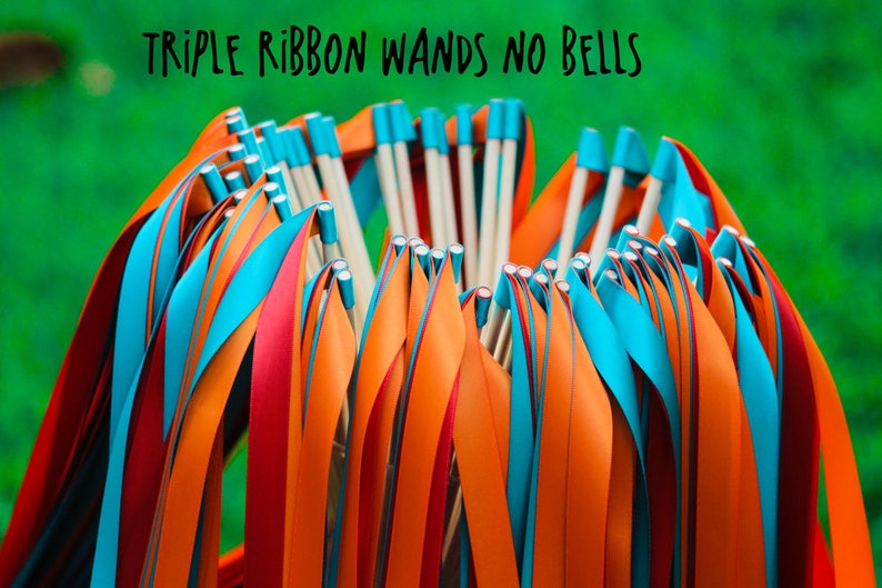 May include: A bunch of triple ribbon wands with orange, red, and blue ribbons. The wands are made of wood and have no bells. The text "TRIPLE RIBBON WANDS NO BELLS" is written above the wands.