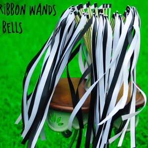 May include: A bunch of black and white ribbon wands with no bells. The wands are tied together and sitting on a small table. The table is on a green grassy surface.