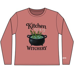 Könnte beinhalten: Ein langärmeliges, staubrosafarbenes Shirt mit einer schwarzen Kessel-Grafik und den Worten "Kitchen Witchery". Der Kessel enthält grüne Kräuter und Dampf. Das Wort "queen" ist auf dem rechten Ärmel aufgedruckt.