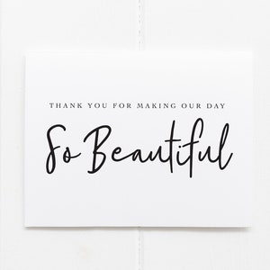 May include: A white card with the text "THANK YOU FOR MAKING OUR DAY So Beautiful" in black script. The card is centered on a white wooden surface.