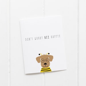 May include: A white card with the text "Don't worry BEE happy!" and a cartoon dog wearing glasses and a bee costume.