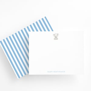 May include: White stationery set with a blue and white striped envelope and a matching notepad. The notepad features a small elephant illustration and the name "BABY HOFFMANN" in blue text. Ideal for baby announcements or thank you notes.