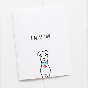 May include: A white card with black text that reads "I miss you." A simple black line drawing of a dog with a blue collar and a red tag is below the text.