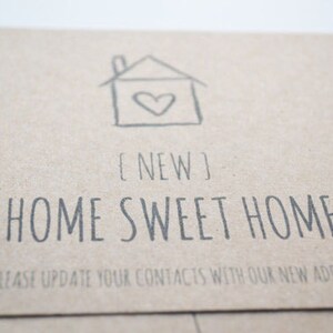 May include: A brown card with a hand-drawn house with a heart inside. The text "[NEW] HOME SWEET HOME" is printed below the house. The text "PLEASE UPDATE YOUR CONTACTS WITH OUR NEW ADDRESS" is printed below the text.