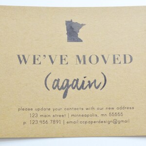 May include: A brown paper card with the text "WE'VE MOVED (again)" and a black outline of the state of Minnesota. The card also includes a new address, phone number, and email address.