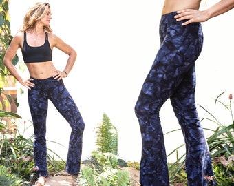 Puede incluir: Una mujer con un sujetador deportivo negro y pantalones acampanados de color azul tie-dye. Los pantalones tienen un patrón azul oscuro y azul claro.