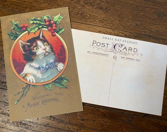 May include: A vintage Christmas postcard featuring a white and brown cat with green eyes wearing a blue bow tie. The cat is looking up and is surrounded by holly and red berries. The text on the postcard reads "Wishing you a Merry Christmas".