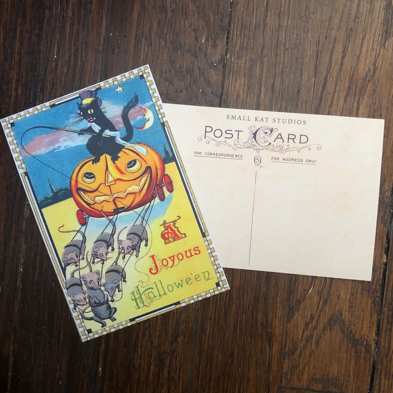 May include: Vintage Halloween postcard featuring a black cat in a top hat riding a jack-o'-lantern carriage pulled by mice. The postcard has the words "Joyous Halloween" and the back of the postcard reads "Post Card" and "Small Kat Studios".